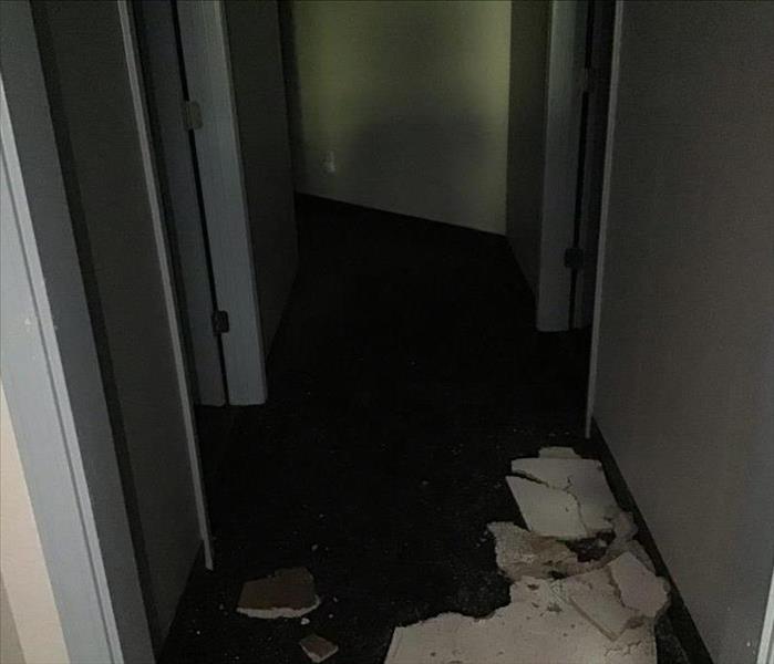 A hallway with broken ceiling and water